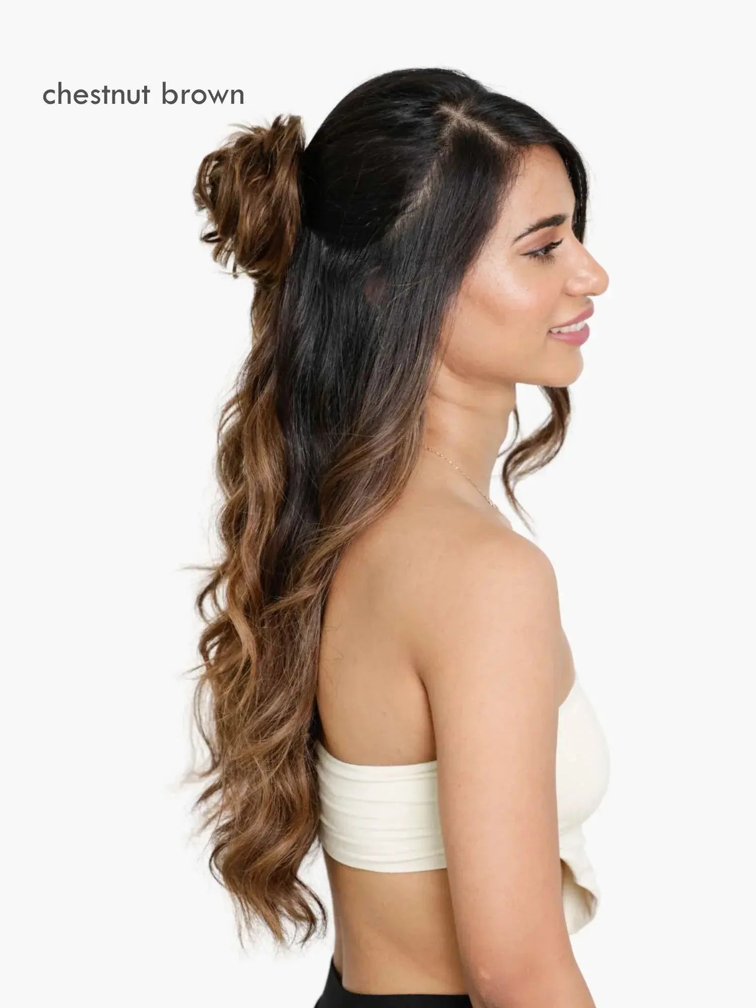 Woman with chestnut brown hair styled in a ponytail with wavy extensions on a white background
