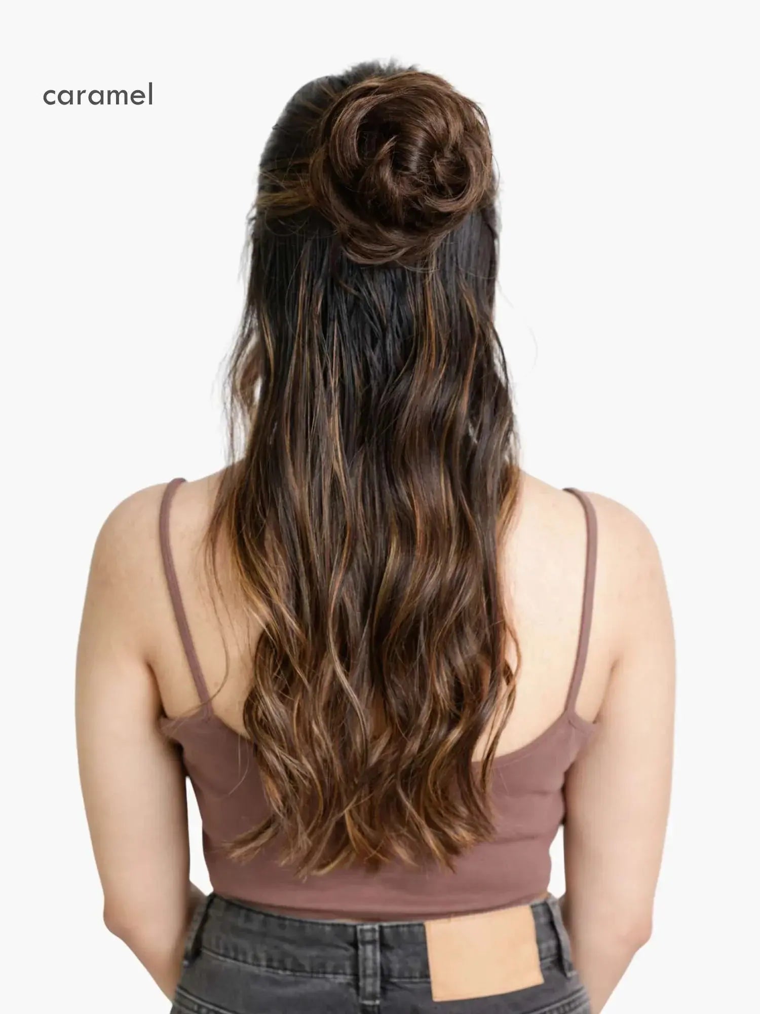 Woman with styled hair in a bun wearing a brown top on a white background